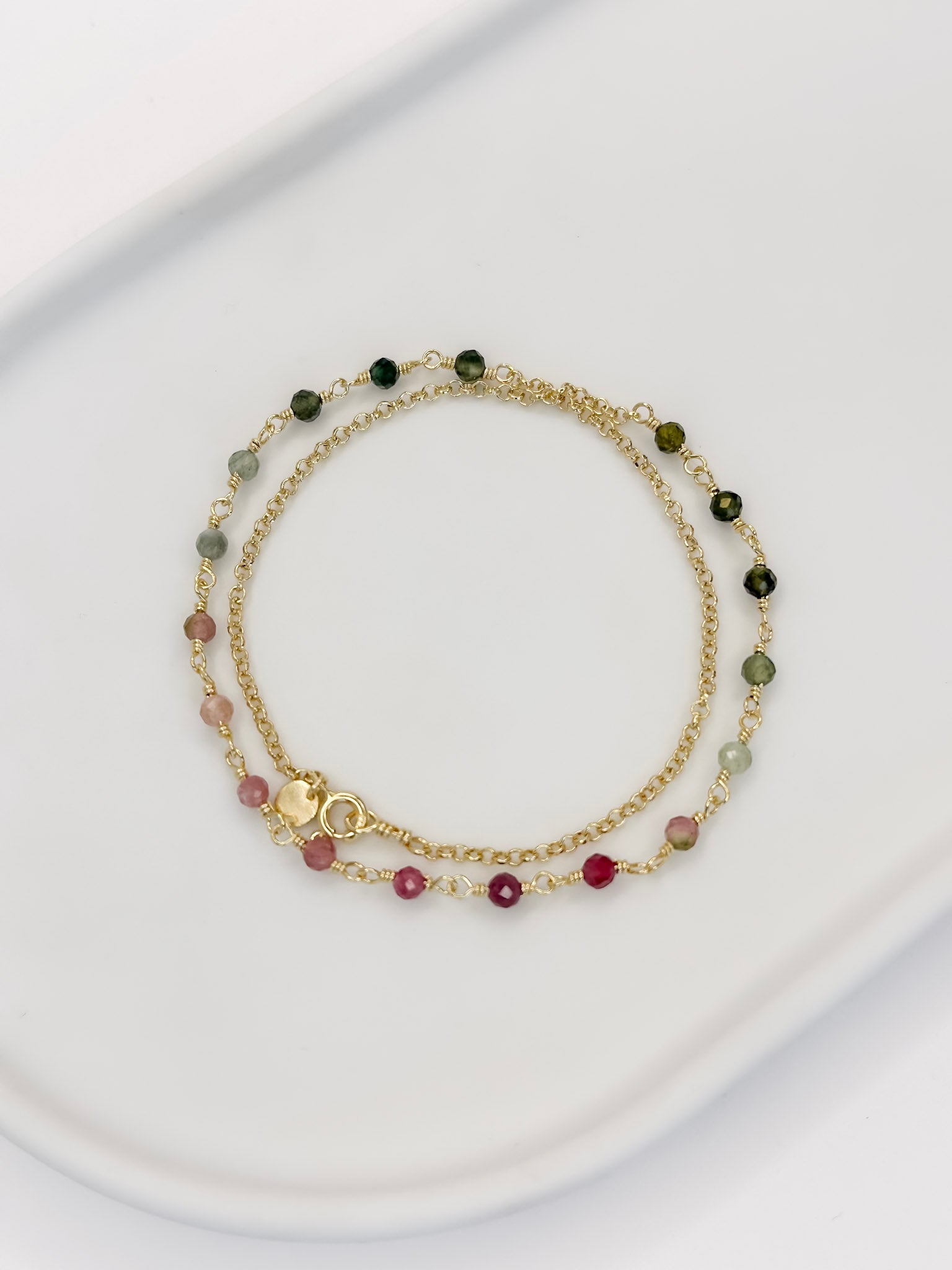 Colar tipo choker que também é Pulseira de duas voltas de corrente portuguesa e turmaina melancia apoiada em uma bandeja branca com fundo branco.