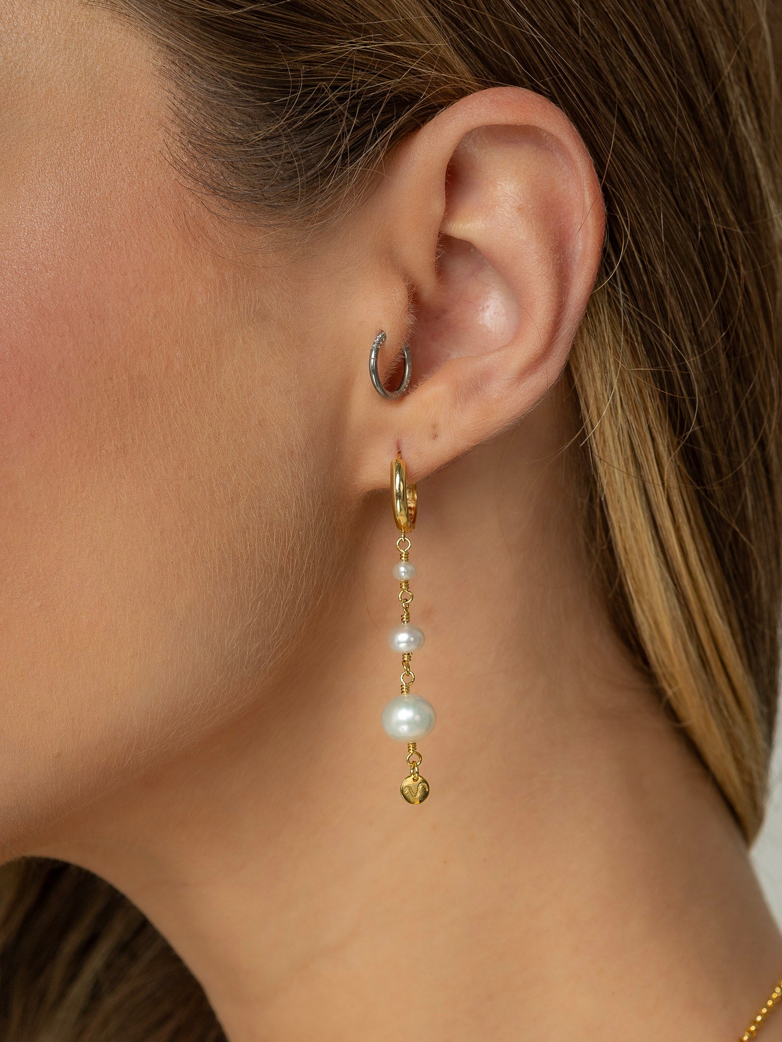 Modelo veste brinco tamanho medio em prata 925 com banho de ouro 18k e tres perolas naturais de diferentes tamanhos. 